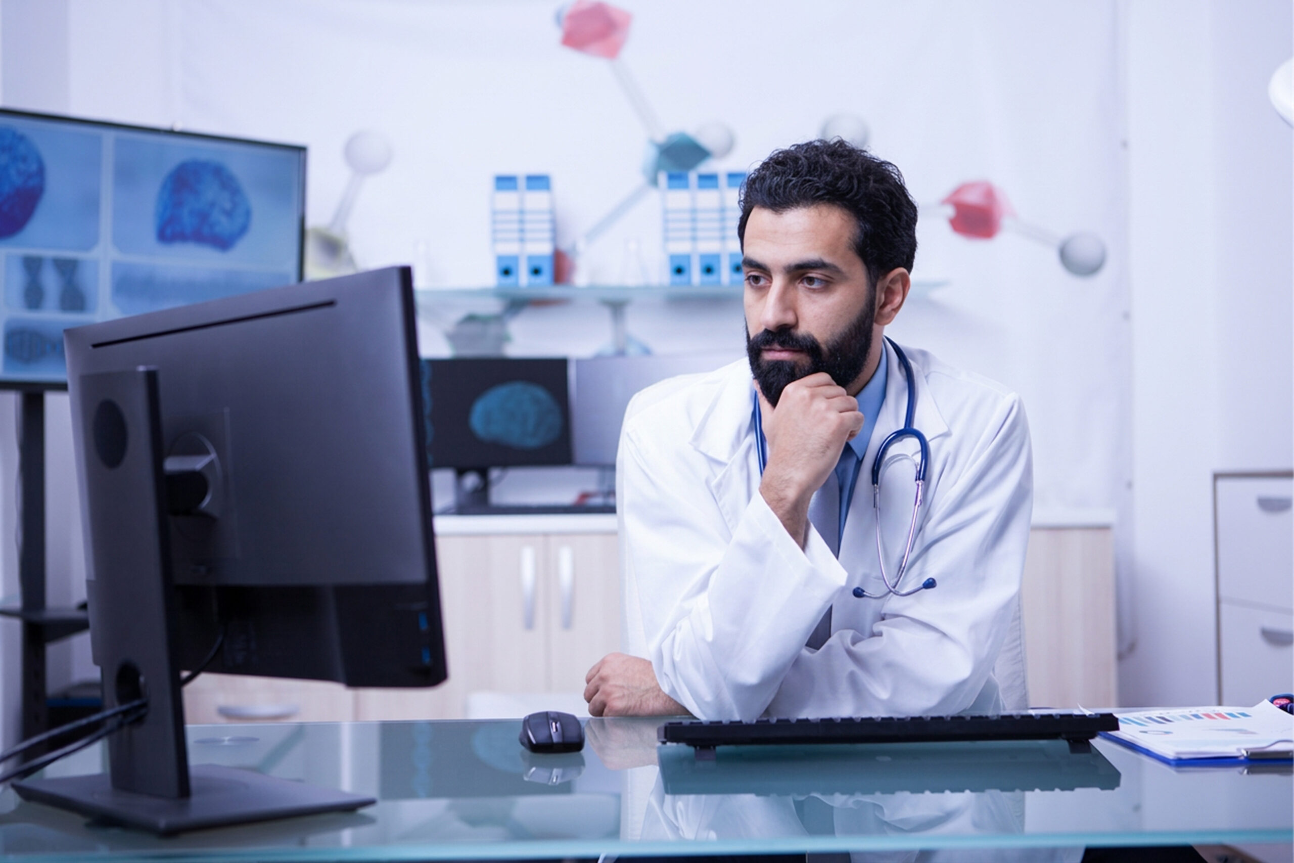 portrait thoughtful young doctor looking into monitor his cabinet doctor using his computer work 1 scaled